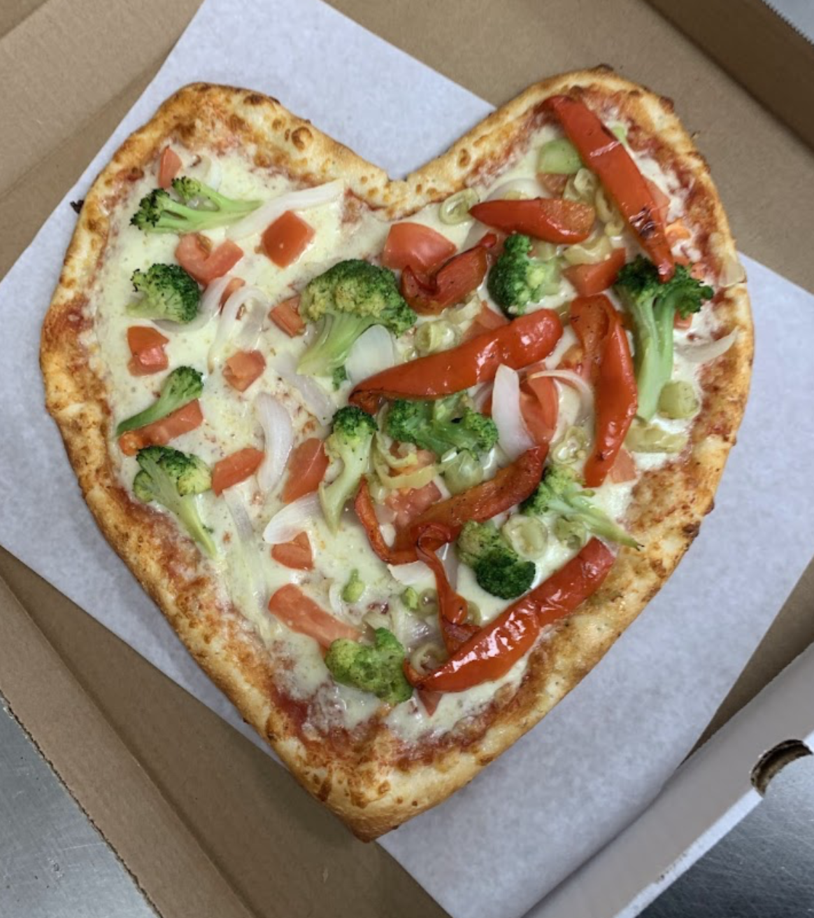 Heart-shaped vegetable pizza in a pizza box